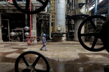 A file photo of a worker walking past oil pipes at a refinery in Wuhan, Hubei province March 23, 2012.