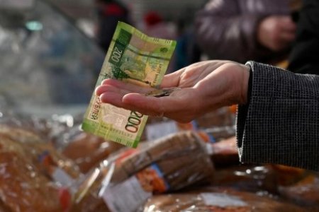 A file photo shows a customer handing over Russian rouble banknotes and coins to a vendor at a market in Omsk, Russia October 29, 2021. 