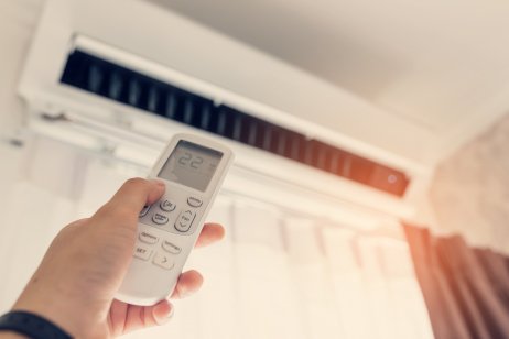 Hand holding a remote against the background of an air conditioner