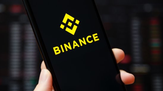 The Binance logo on a phone in front of a price graph