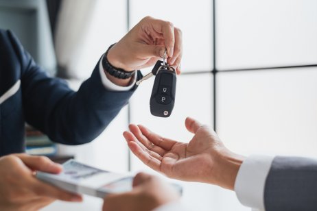 A car dealer hands over a set of vehicle keys