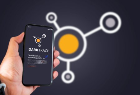 A picture of a hand holding a phone with the Darktrace company logo on a screen behind