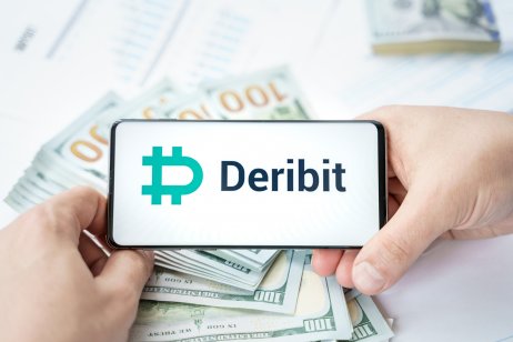 Deribit's logo on a phone, which is in front of cash