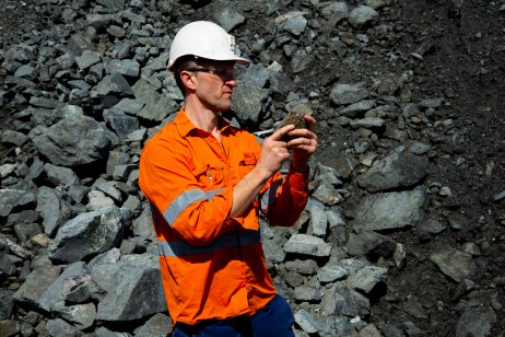Geologist examining mineral content of a rock formation Geologist examining mineral content of a rock formation