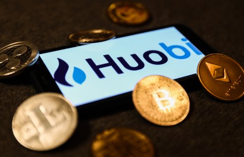 Huobi logo displayed on a smartphone surrounded by representations of cryptocurrencies
