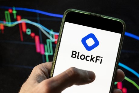  In this photo illustration the Blockfi logo seen displayed on a smartphone with an economic stock exchange index graph in the background