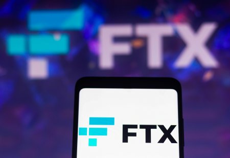 The FTX crypto derivatives exchange logo is displayed on a smartphone screen and in the background