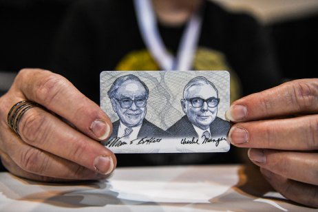 Woman shows a card with photos of Warren Buffett (L) and Charlie Munger (R) 