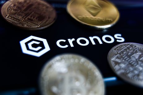 Cronos logo displayed on a phone screen and representation of cryptocurrencies are seen in this illustration photo taken in Krakow, Poland