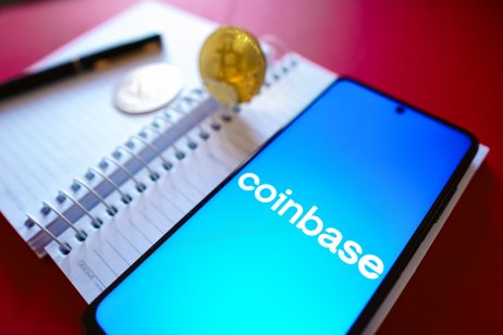 Coinbase logodisplayed on a smartphone screen beside Bitcoin cryptocurrencies