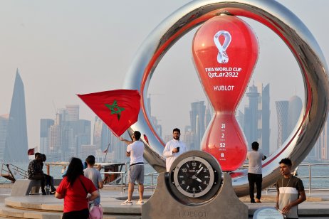 A picture taken on 20 October, 2022, shows people walking past the Qatar 2022 FIFA World Cup countdown clock as it nears marking thirty days, in the Qatari capital Doha