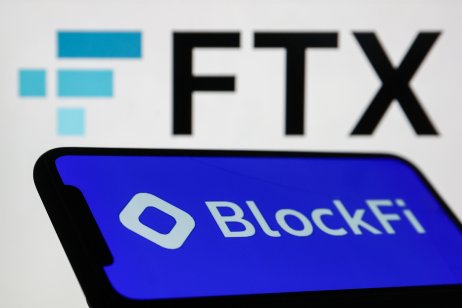 BlockFi name and logo displayed on a phone with the FTX logo behind on a laptop screen