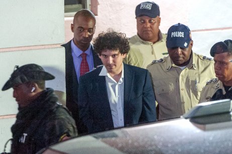  FTX founder Sam Bankman-Fried (C) is led away handcuffed by officers of the Royal Bahamas Police Force in Nassau, Bahamas on 13 December, 2022