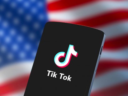 Een afbeelding van TikTok op een smartphone met de Amerikaanse vlag op de achtergrond