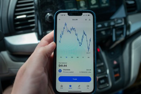 hand holding an iPhone displaying chart of the price of Chainlink cryptocurrency 
