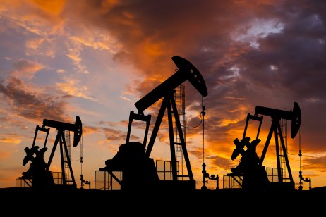 Oil field with rigs and pumps at sunset