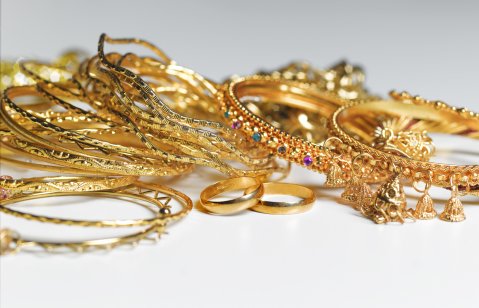 A variety of gold jewellery against a plain background