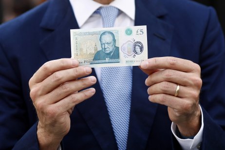 Suited businessman holding a five pound note