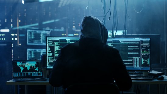 Silhouette of a hacker at work in his computer lair