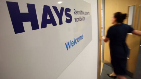 An office worker walks past a sign bearing the company name Hays