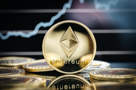 An Ethereum gold coin in front of a price chart