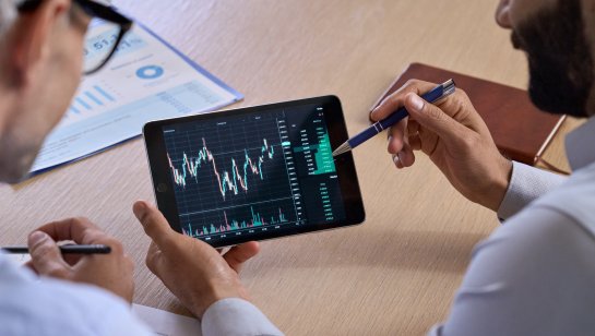 People examine a trading chart on a tablet