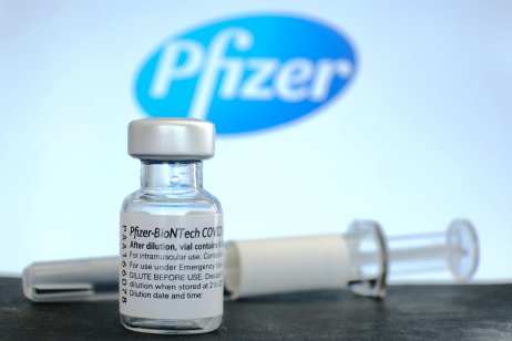 A Pfizer logo, bottle and vaccine needle