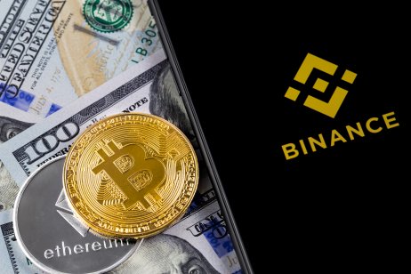 Binance logo, bitcoin, ether and US dollar on desk