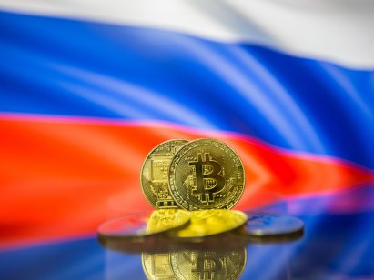 Bitcoin coins in front of a Russian flag