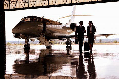 Corporate jet outside hanger with two people walking