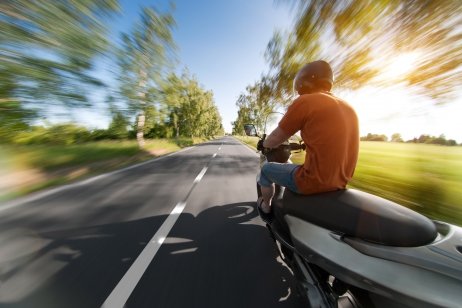 An image of a man riding a scooter at high speeds