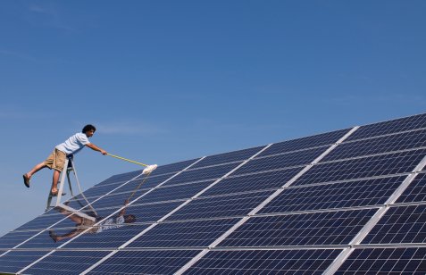 A man stands on a ladder to clean solar panes, in New Jersey, US.