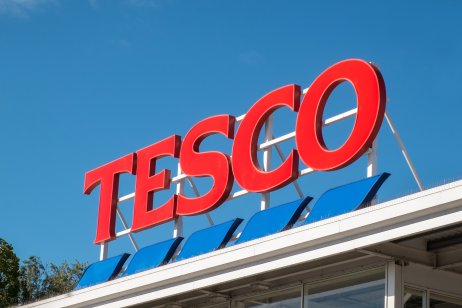 Red and blue Tesco sign set against a bright sky