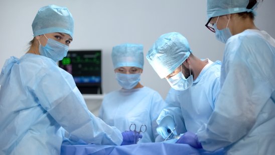 Surgeons stand around an operating table