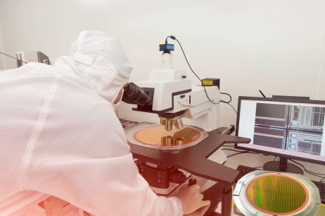 Technician checking silicon wafer using microscope