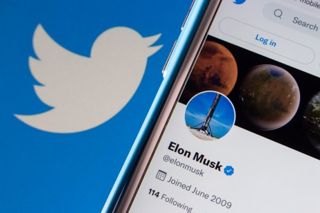 A smartphone shows Elon Musk's Twitter profile next to the Twitter bird logo