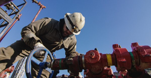 An oilfield worker pumps down lines at an oil and gas drilling pad in the US. 