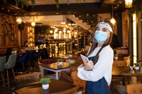 Waitress in face mask and shield in compliance with Covid-19 rules 