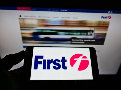 A picture of a person holding mobile phone with FirstGroup logo in front of business web site