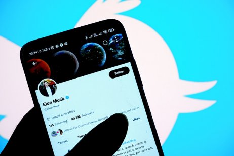 Elon Musk’s Twitter account is displayed on the screen of an iPhone in front of the homepage of the Twitter website 