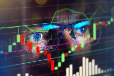 A market trader reflected in a trading chart shown on a screen