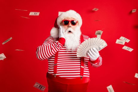 Photo of figure with Santa hat, striped top and red braces holding cash fan in hand