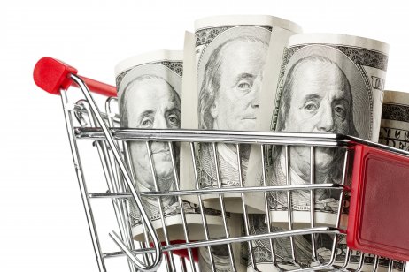 Close-up of a shopping cart and dollars on a white background