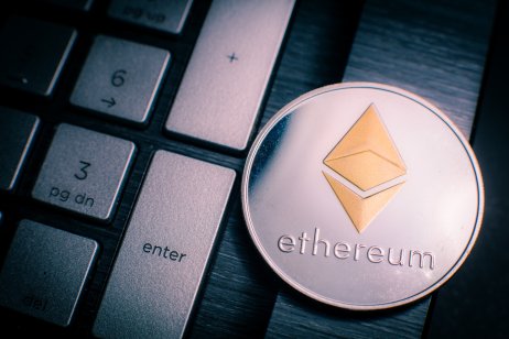 Silver Ether coin with gold Ethereum symbol on a laptop keyboard