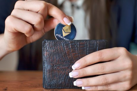Woman's hands put crypto coin into a wallet