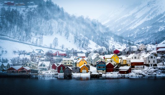 Wooden houses on the shore of the Norwegian fjord, beautiful mountain landscape in winter
