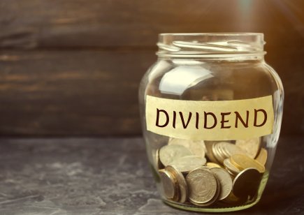 Glass jar holding coins with the word Dividend