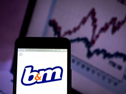B & M European Retail Value S.A. company logo displayed on smart phone in front of a graph