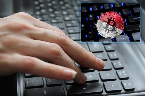 A hand on the keyboard and screen showing cryptocurrency with Indonesian flag