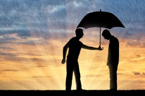 A silhouette of a man holding an umbrella over another man's head